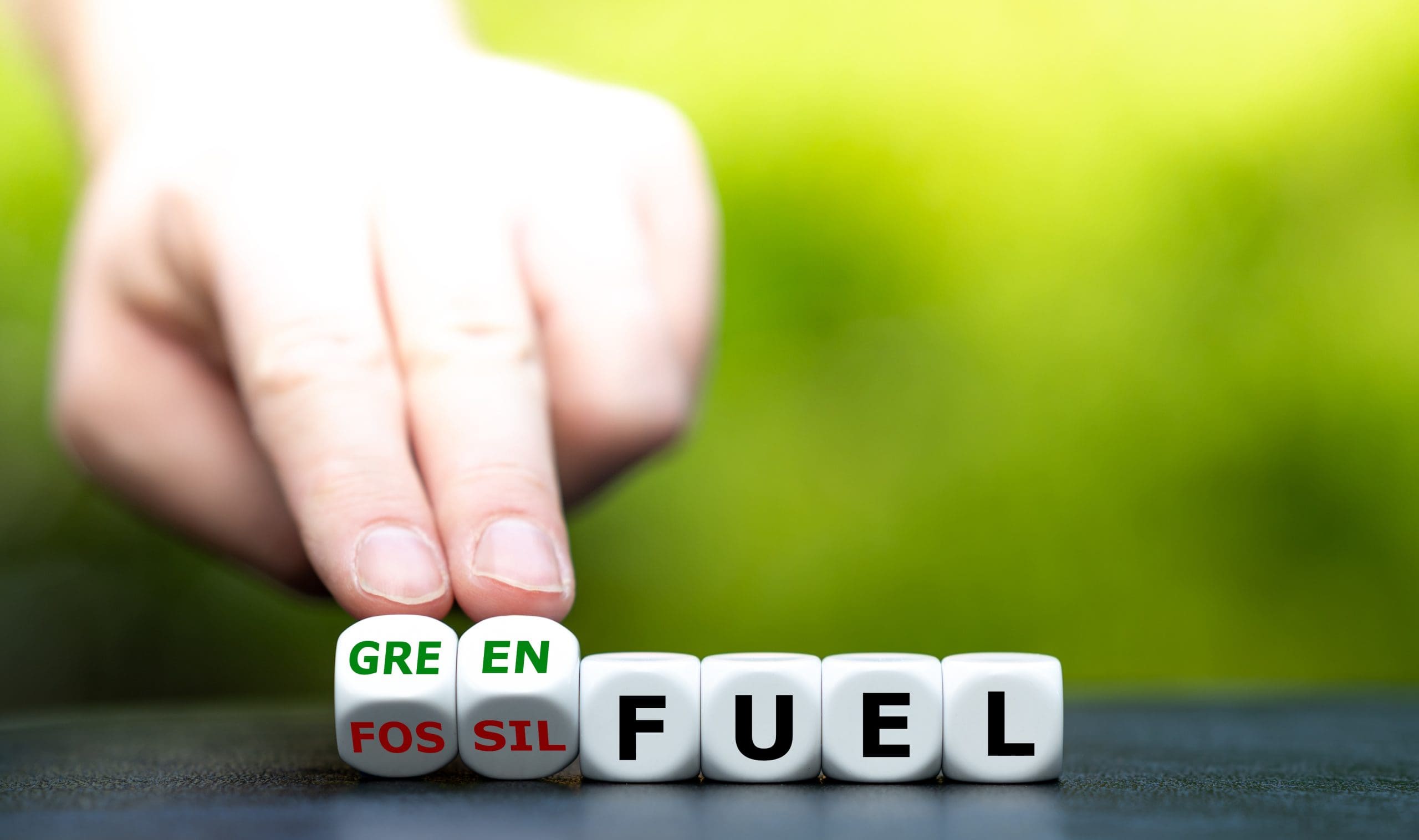 Hand turns dice and changes the expression “fossil fuel” to “green fuel”.
